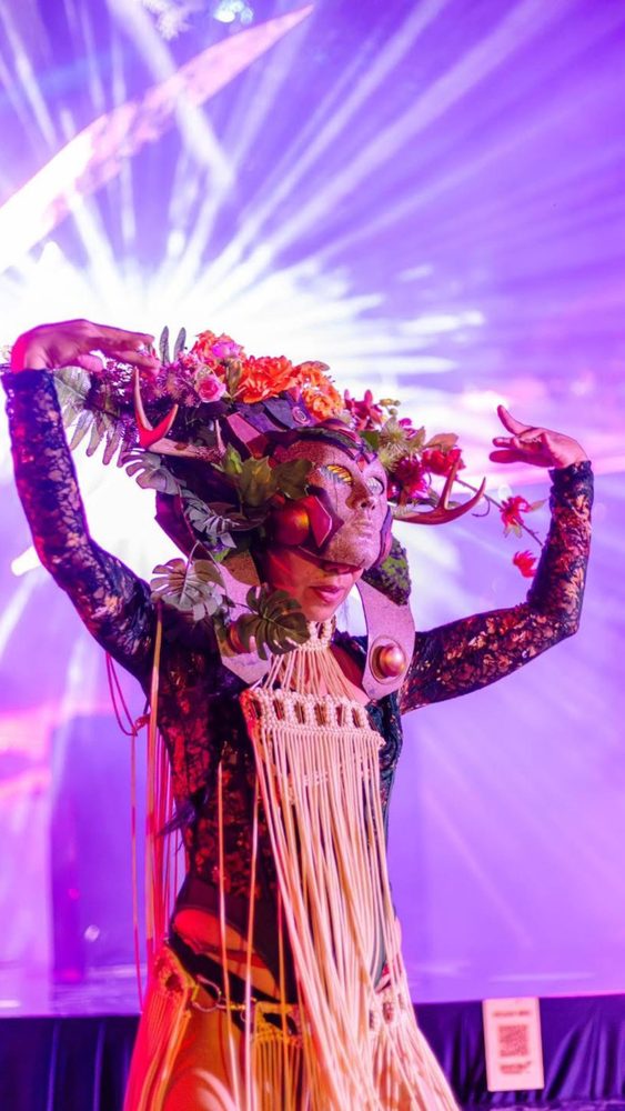 Performer in a floral headpiece and mask on stage at Tulum Wedding Week 2026